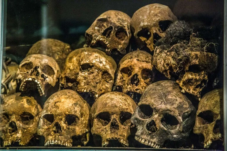 Gestapelte, alte Schädel in verschiedenen Rottönen und Zerfallsstadien in einer Vitrine ausgestellt