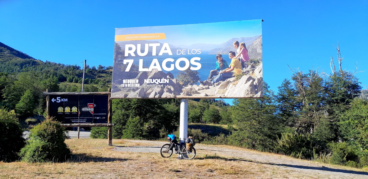 Große Werbetafel für Ruta de los 7 Lagos in Patagonien, Neuquén, mit Fahrrad im Vordergrund und bergiger Landschaft