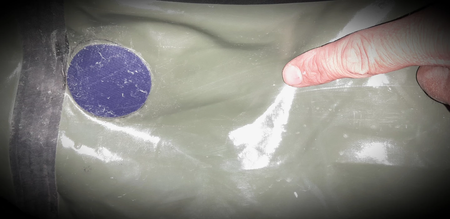 Nahaufnahme einer glatten, grauen Oberfläche mit einem violetten Kreis und einem rosa Finger am rechten Bildrand