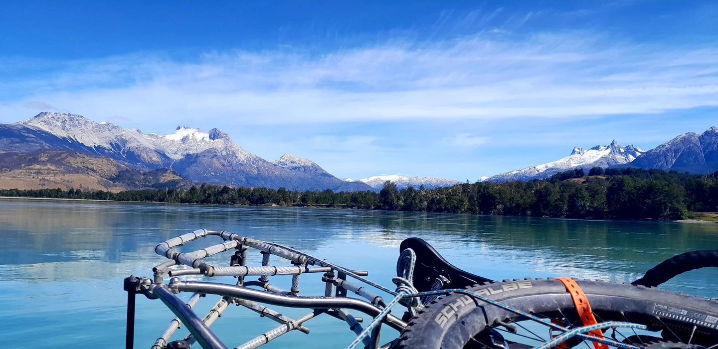 Fahrradlenker mit Blick auf türkisfarbenen See und schneebedeckte Berge in Patagonien