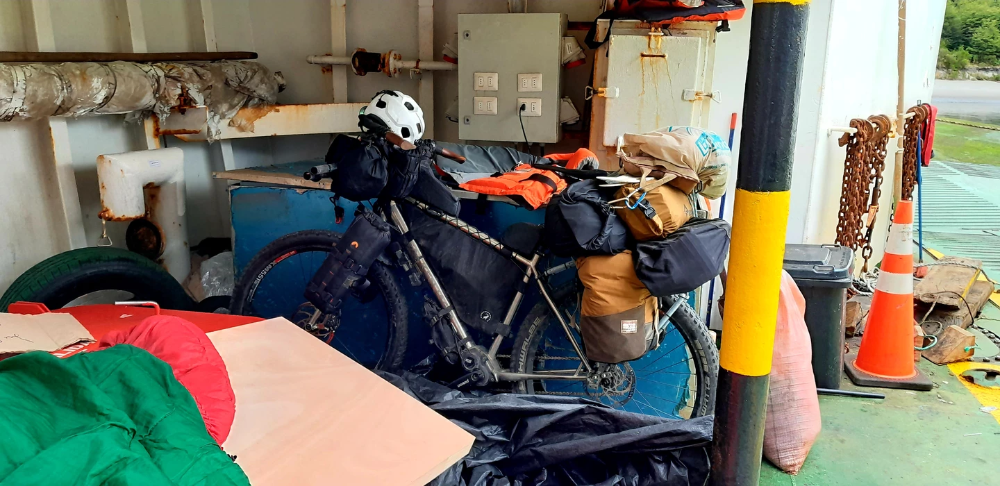 Schwarz-orangefarbenes Fahrrad mit Bikepacking-Taschen und Gepäck, verstaut in einem unordentlichen Laderaum mit Elektrokasten und Verkehrskegel