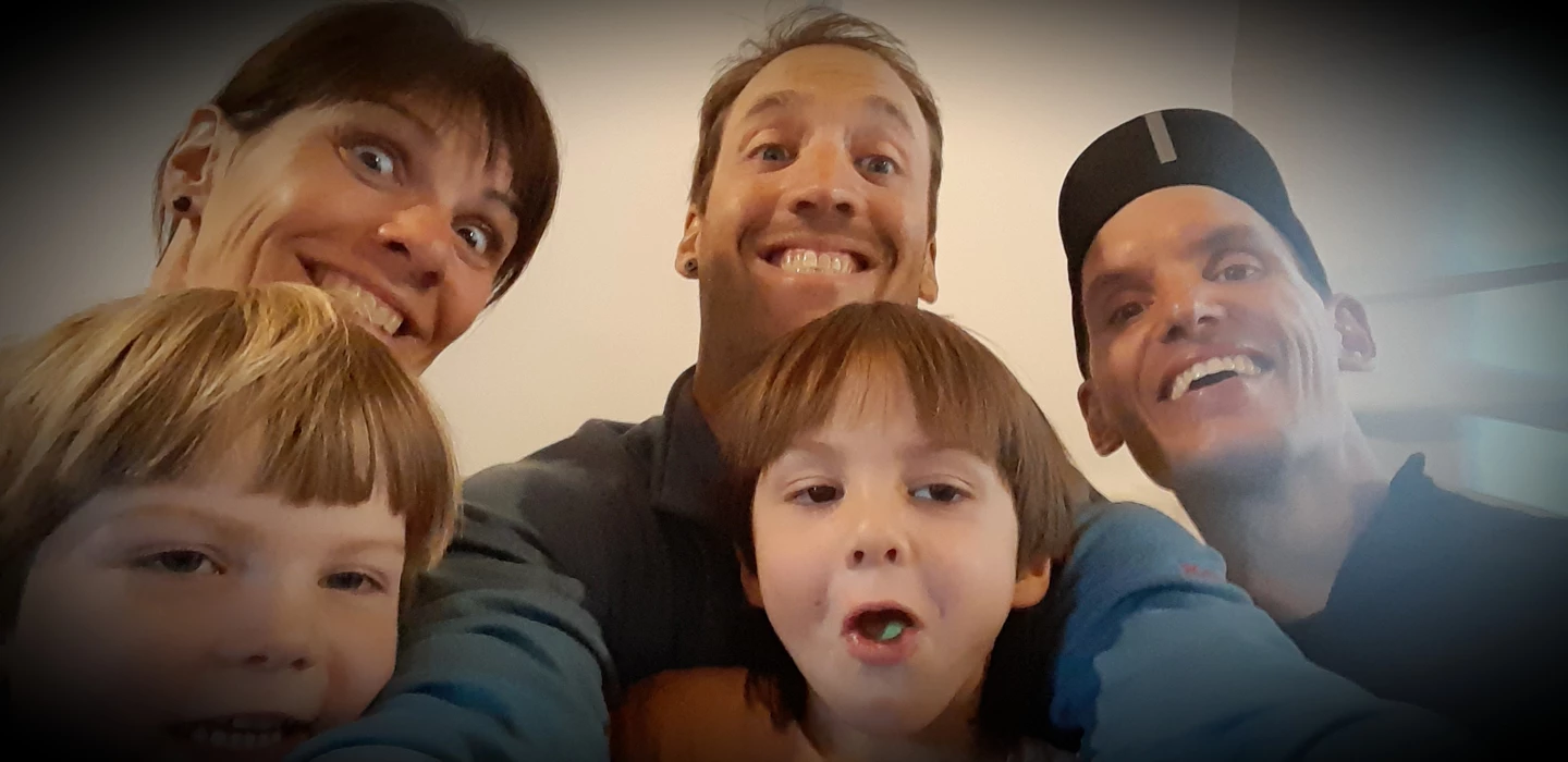 Nahaufnahme von vier lächelnden Gesichtern, drei Erwachsene und ein Kind, eng zusammengedrängt in einem Selfie