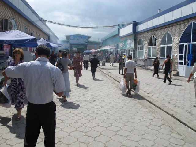 Belebter Marktplatz mit Menschen, die zwischen Verkaufsständen und Gebäuden mit blauen Elementen umherlaufen