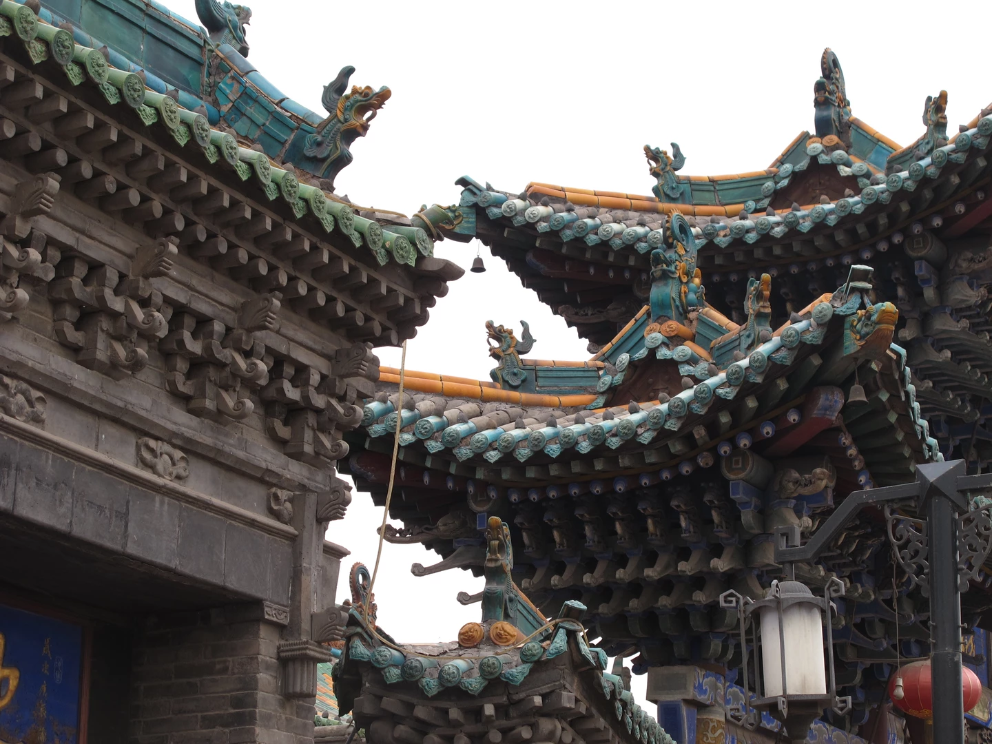 Detailreiche Dachkonstruktion eines chinesischen Gebäudes mit kunstvoll gestalteten Firstziegel und Drachenornamente in Blau- und Grüntönen