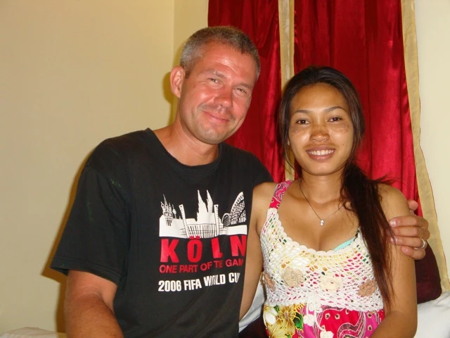 Mann in schwarzem Köln-Shirt und lächelnde Frau in gemustertem Top stehen nebeneinander