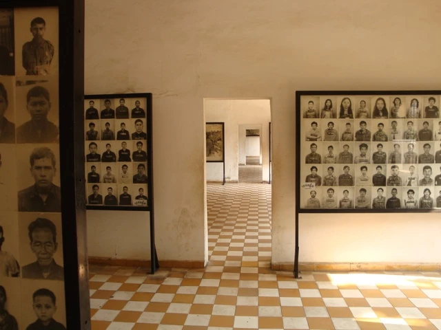 Ausstellungsraum mit Wänden voller Schwarz-Weiß-Porträts von Gefangenen, Schachbrettboden, Durchgang