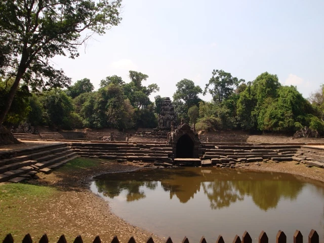 Historische steinerne Terrassen mit zentralem Wasserbecken, umgeben von dichten Bäumen und Vegetation in Kambodscha