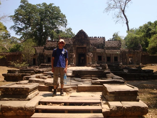 Steinerne Tempelruine mit verfallenen Mauern und Torbögen, Person steht auf vorderen Steinstufen