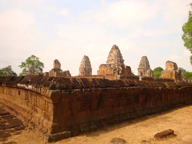 Historische Steinmauer mit mehreren verfallenen Türmen aus der Khmer-Architektur in Kambodscha, Sandsteinblöcke und Ruinen