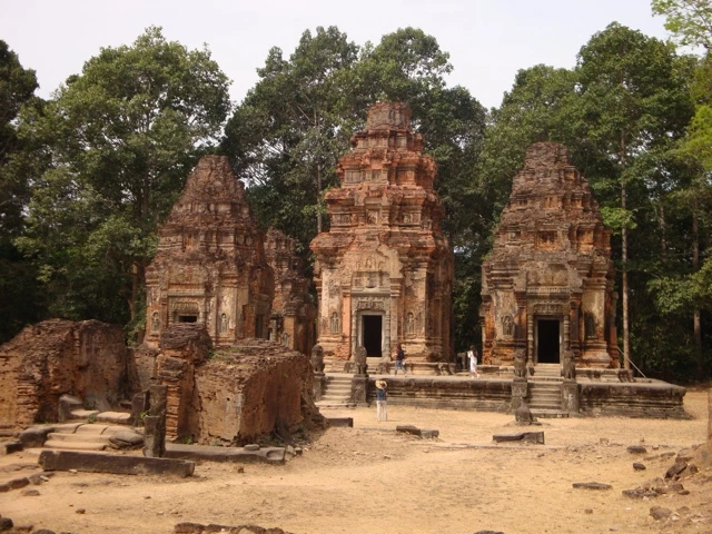 Drei historische Sandsteintempel in Kambodscha, umgeben von Bäumen, mit Säulen und Eingängen