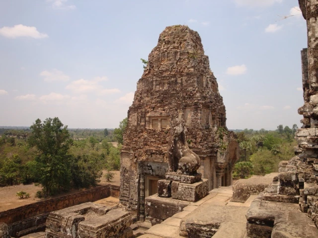 Alter Steinturm aus Ziegelsteinen in Kambodscha, umgeben von Ruinen und grüner Landschaft