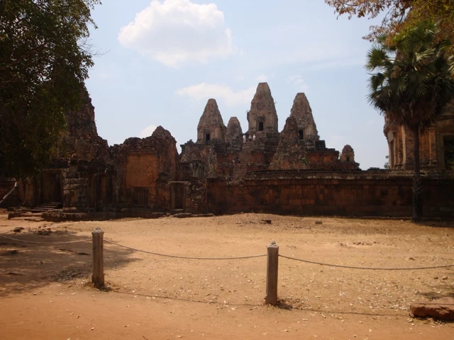 Historische Sandsteinruinen mit spitzen Türmen in Kambodscha, Tempelanlage Pre Rup mit rötlichen Steinen und Palmen