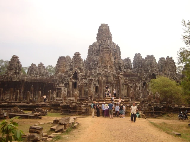 Historische Steinarchitektur des Bayon-Tempels mit mehreren Türmen und Besuchern auf sandigem Vorplatz