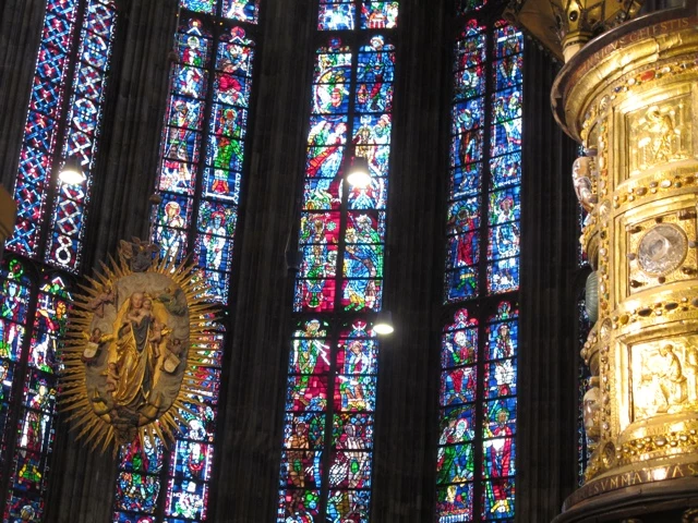 Farbenfrohe gotische Kirchenfenster mit mittelalterlichen Glasmalereien in Blau, Rot und Grün, goldene Verzierungen seitlich