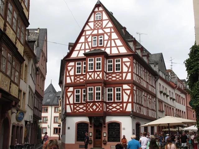 Historisches Fachwerkhaus in rot-weißer Bauweise in einer mittelalterlichen Altstadtgasse mit Touristen