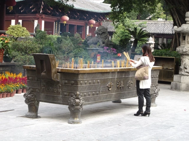 Große bronzene Räucherschale mit brennenden Räucherstäbchen vor traditionellem chinesischem Tempelgebäude in Hongkong