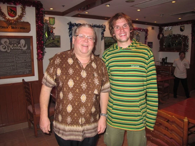 Zwei lächelnde Männer in unterschiedlich gemusterten Pullover - einer in braun-beige, der andere in grün-gelben Ringeln