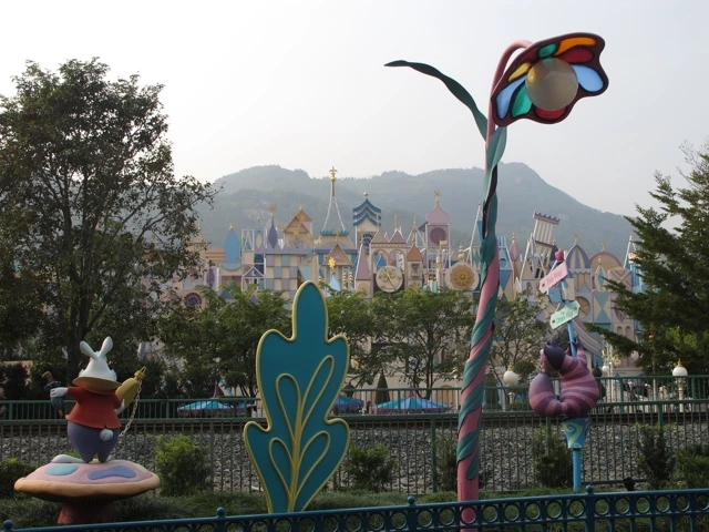 Bunte Märchenfiguren und Dekorationen vor dem Schloss von Disneyland Hong Kong mit Bergen im Hintergrund