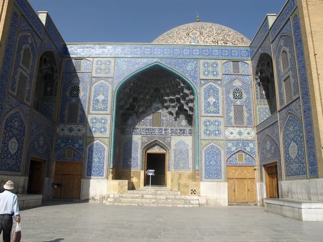 Historische islamische Moschee mit türkis-blauer Kachelung, großem Rundbogen-Eingang und Kuppeldach in sonniger Umgebung