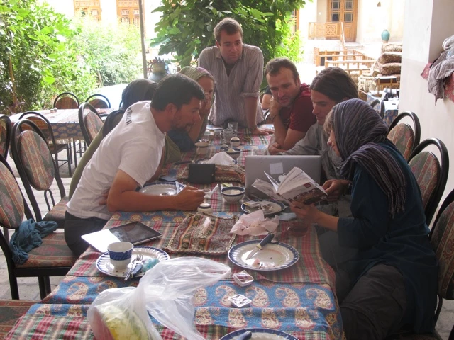 Gruppe von Menschen sitzt an einem gedeckten Tisch mit Tee und Tellern in einem traditionellen Teehaus im Iran