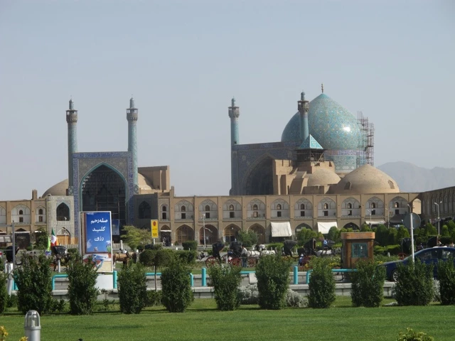 Blick auf die blaue Kuppelmoschee mit Minaretten auf dem Imam-Platz in Isfahan, umgeben von Arkaden und Grünflächen