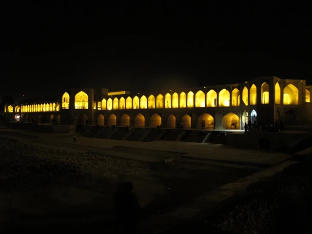 Beleuchtete Steinbrücke mit Bögen und Arkaden in dunkler Nacht, traditionelle persische Architektur