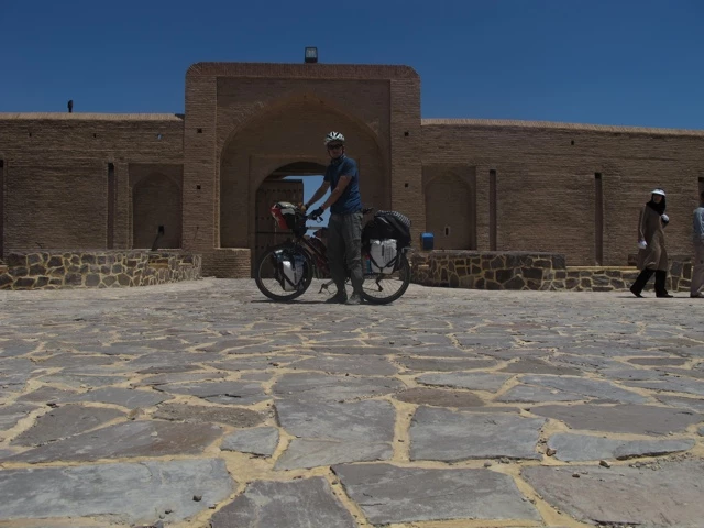 Steinerne Festung mit Rundbogentor, Radfahrer mit Gepäck und Helm steht auf gepflastertem Vorplatz