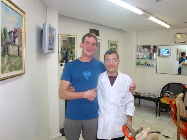 Mann in blauem T-Shirt mit weißem Kittel-Träger in hellem Behandlungsraum mit Wandbildern