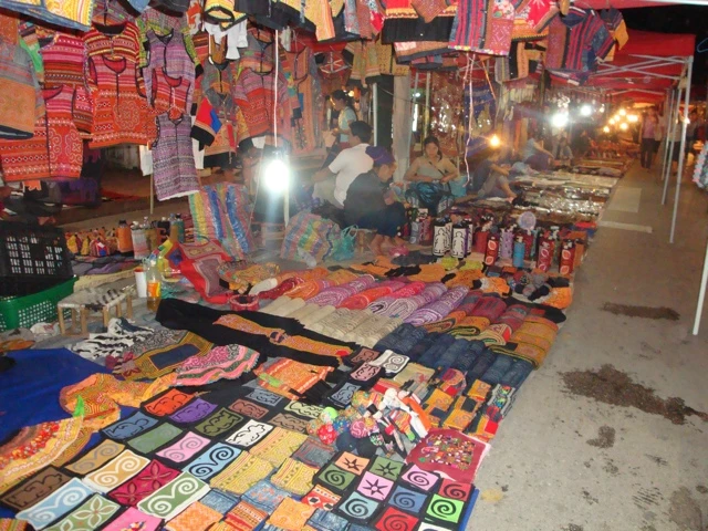 Nachtmarkt mit vielen bunten Stoffen, Decken und Textilien, ausgebreitet auf Böden und Ständen, gedämpftes Licht