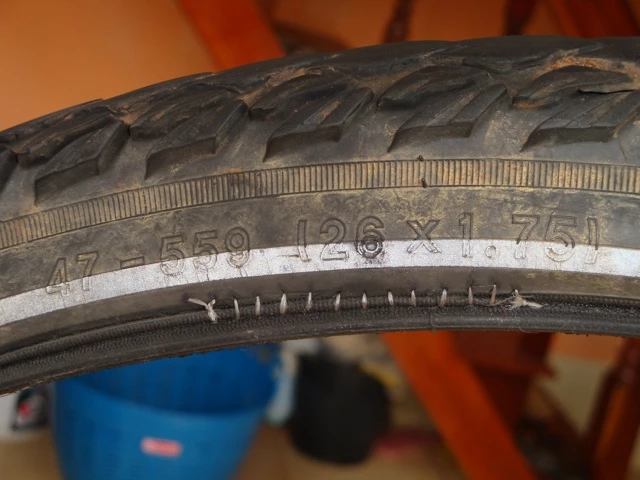 Nahaufnahme eines abgenutzten Fahrradzreifens mit sichtbarer Reifengröße 26x1.75 und Verschleißspuren