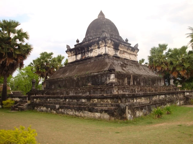 Steinerner Tempelturm mit Kuppeldach, umgeben von Palmen, auf einer Grünfläche stehend, alte Architektur