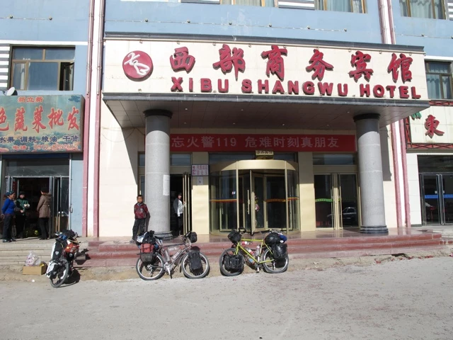 Eingang des Xibu Shangwu Hotels mit mehreren geparkten Fahrrädern im Vordergrund und weißer Fassade