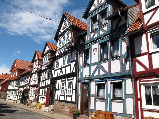 Reihe traditioneller Fachwerkhäuser mit rot-weißen Holzfassaden in einer schmalen Straße einer deutschen Kleinstadt